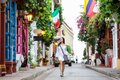 Beautiful woman on white dress walking alone at the colorful streets of the colonial walled city of Cartagena de Indias